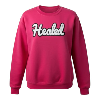 Pink sweatshirt with 'Healed' text on a white background